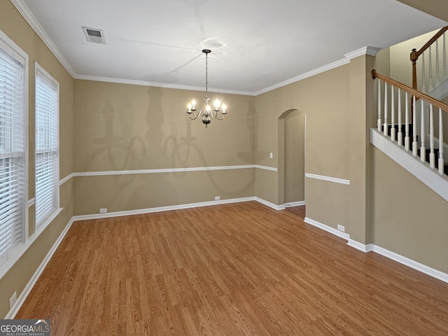 unfurnished room featuring crown molding, wood-type flooring, and an inviting chandelier