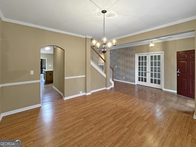 unfurnished dining area with hardwood / wood-style floors, a notable chandelier, ornamental molding, and french doors