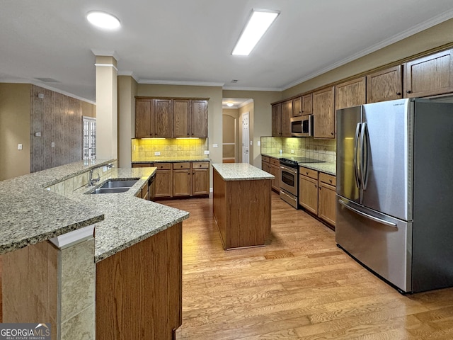 kitchen with a center island, sink, light hardwood / wood-style flooring, ornamental molding, and stainless steel appliances