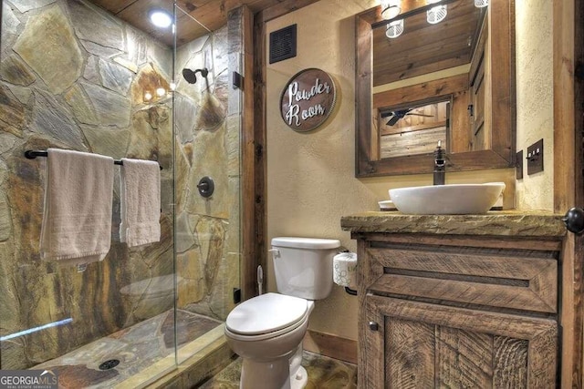 bathroom featuring a shower with shower door, vanity, and toilet