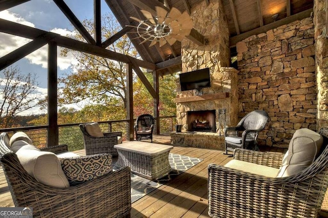 sunroom with an outdoor stone fireplace, ceiling fan, and vaulted ceiling with beams