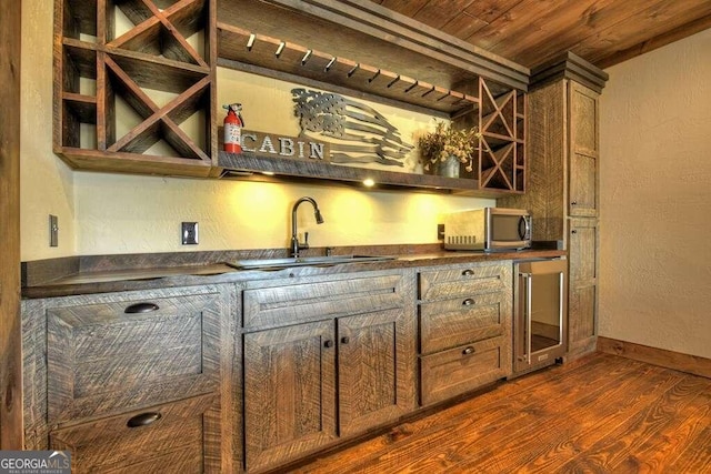 bar featuring dark wood-type flooring, sink, beverage cooler, and wood ceiling