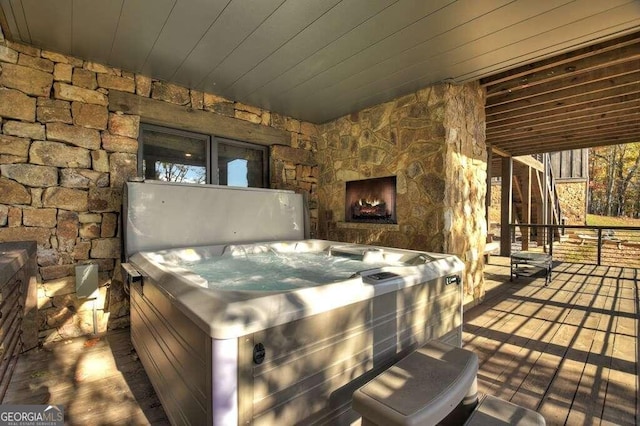 wooden deck featuring a stone fireplace and a hot tub