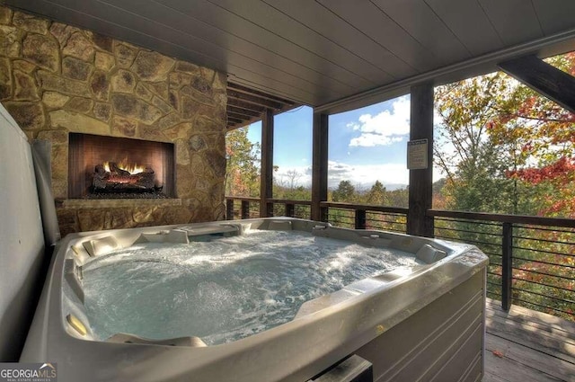 deck with a hot tub and an outdoor stone fireplace