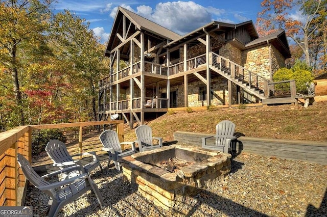 rear view of house featuring a wooden deck and a fire pit