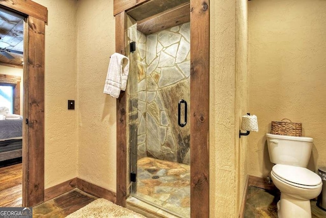 bathroom with toilet and a shower with door