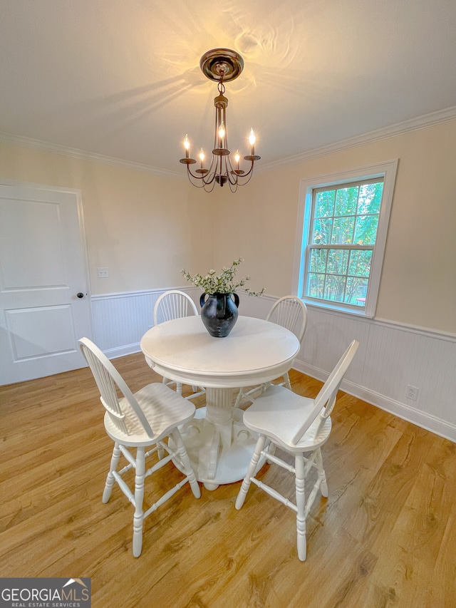 dining area featuring light wood-type flooring, a notable chandelier, and crown molding