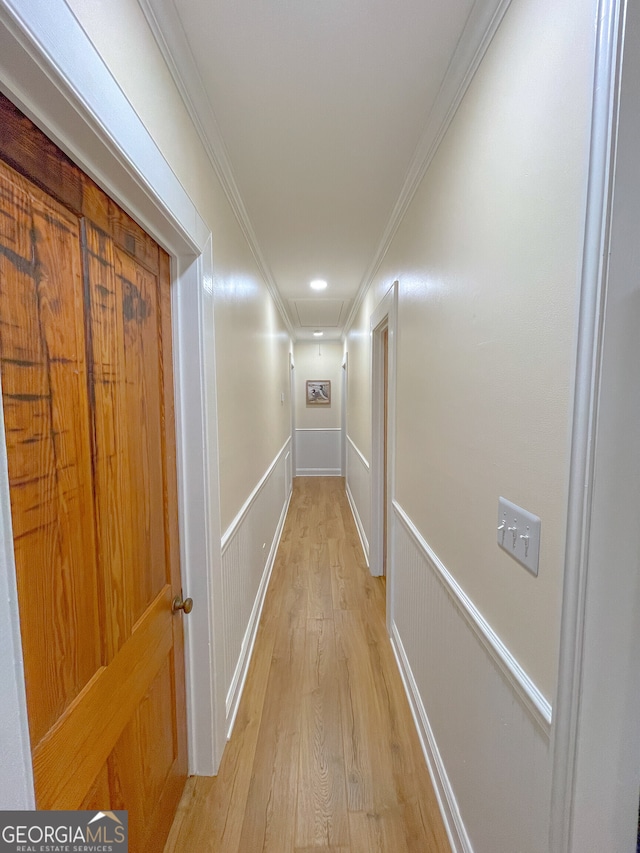 hallway with light wood-type flooring and ornamental molding