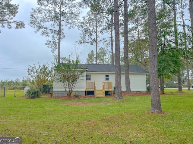 rear view of property featuring a wooden deck and a lawn