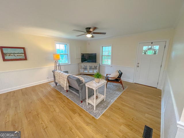 living room featuring ornamental molding, ceiling fan, and light hardwood / wood-style flooring