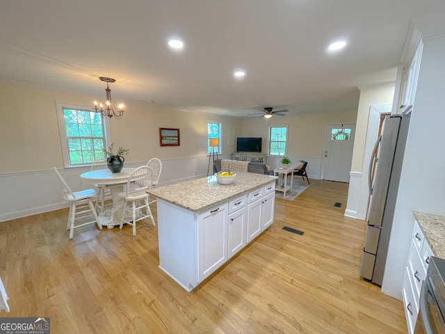 kitchen featuring refrigerator, white cabinetry, light wood-type flooring, and a kitchen island