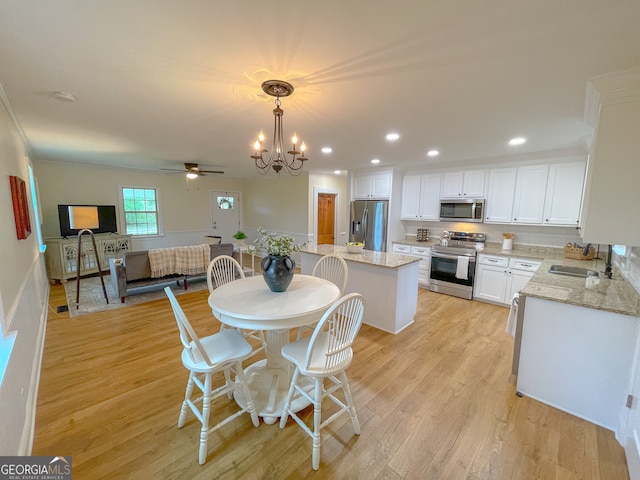 dining room with light wood-type flooring, ceiling fan with notable chandelier, and sink