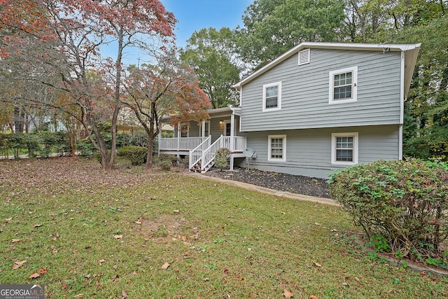 rear view of property featuring a lawn and covered porch