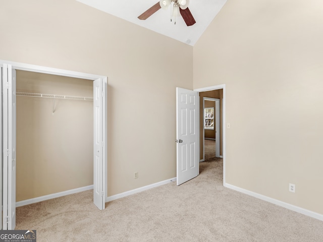 unfurnished bedroom featuring ceiling fan, light carpet, high vaulted ceiling, and a closet