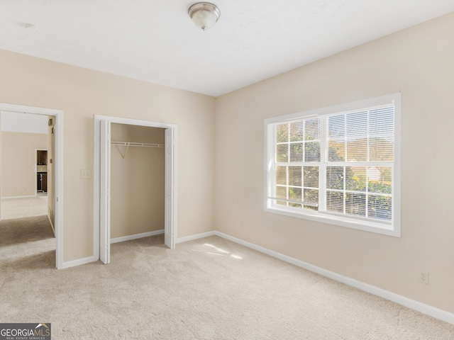 unfurnished bedroom with light colored carpet and a closet