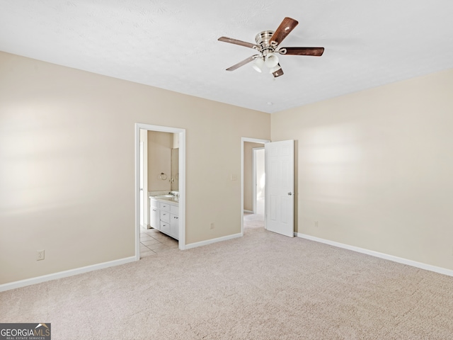 unfurnished bedroom featuring ceiling fan, light colored carpet, and connected bathroom