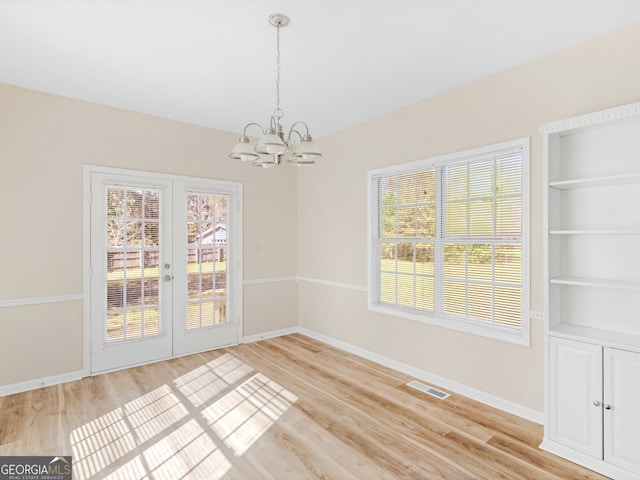 unfurnished dining area featuring a chandelier, light hardwood / wood-style flooring, and built in features