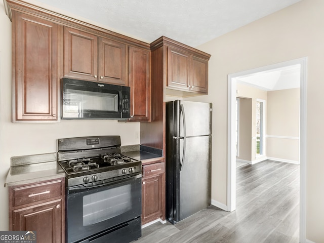 kitchen with light hardwood / wood-style flooring and black appliances