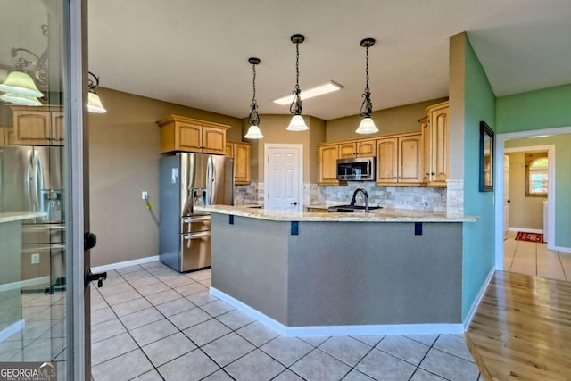 kitchen featuring light stone counters, kitchen peninsula, backsplash, pendant lighting, and appliances with stainless steel finishes