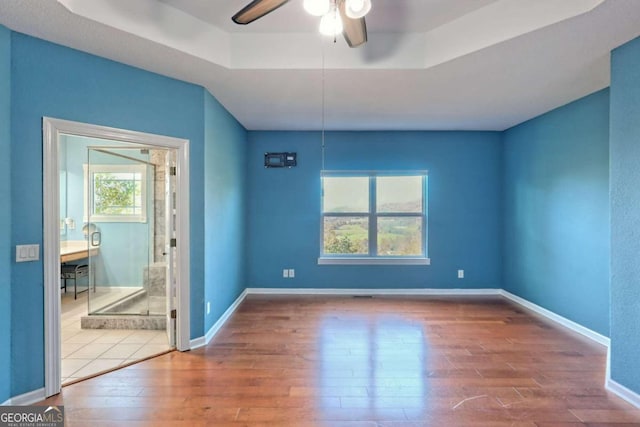 unfurnished room featuring hardwood / wood-style flooring, ceiling fan, and a tray ceiling