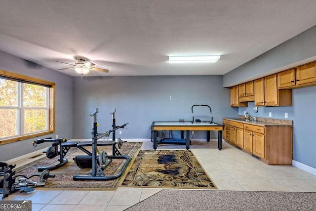 exercise room featuring ceiling fan, light tile patterned floors, and sink