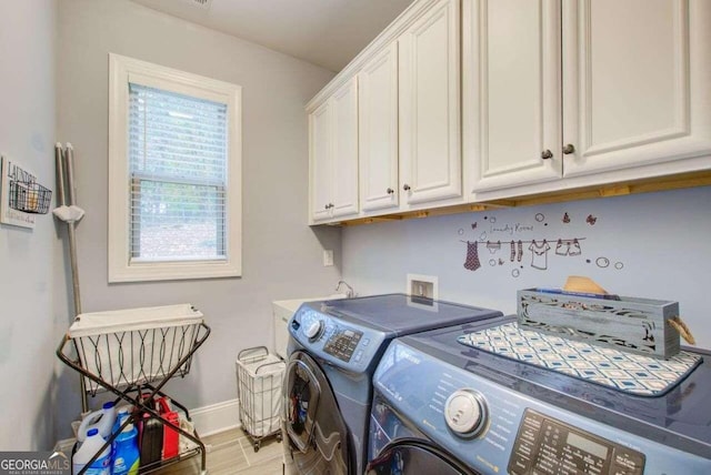 clothes washing area featuring washer and clothes dryer, light wood-type flooring, and cabinets