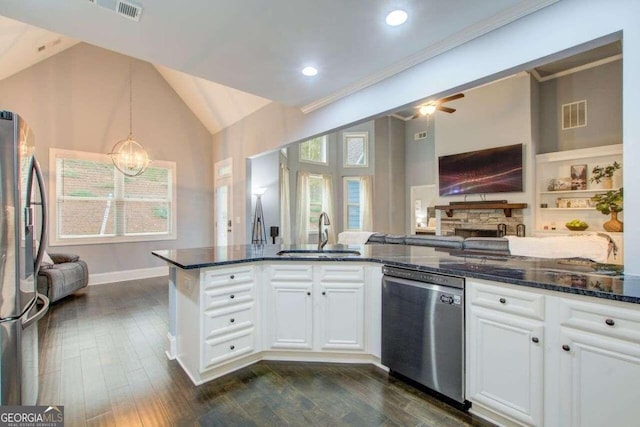 kitchen with stainless steel appliances, vaulted ceiling, hanging light fixtures, sink, and white cabinetry