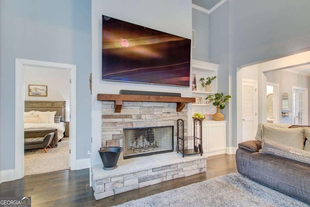 living room with a fireplace, a high ceiling, dark wood-type flooring, and crown molding