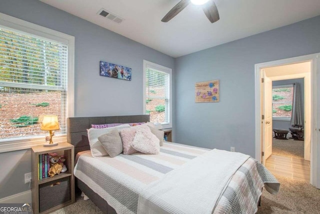 carpeted bedroom with ceiling fan and multiple windows