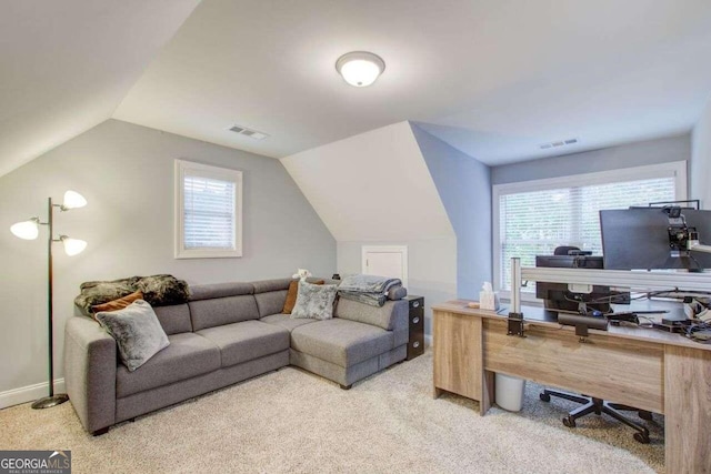 office space featuring lofted ceiling, light colored carpet, and plenty of natural light