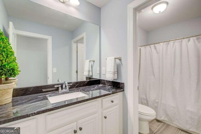 bathroom with toilet, a shower with curtain, and vanity