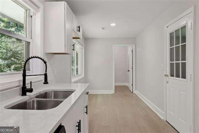 kitchen with white cabinetry, a healthy amount of sunlight, and light wood-type flooring