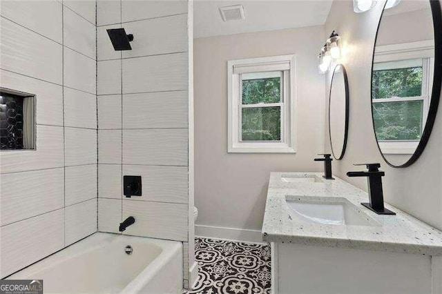 full bathroom featuring vanity, tile patterned flooring, a healthy amount of sunlight, and tiled shower / bath combo