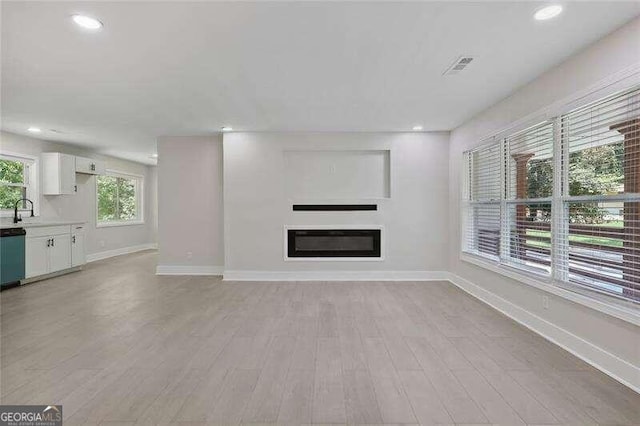 unfurnished living room with light wood-type flooring and sink