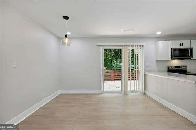 unfurnished dining area featuring light wood-type flooring