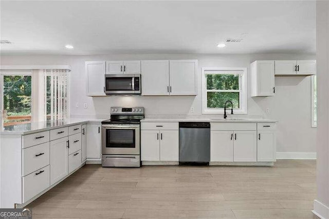 kitchen with white cabinets, appliances with stainless steel finishes, sink, and plenty of natural light