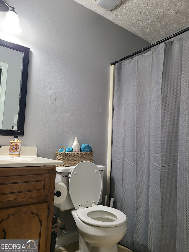 bathroom featuring vanity, a textured ceiling, and toilet