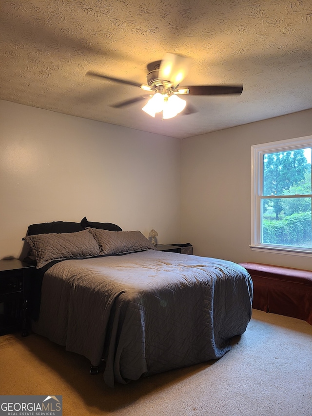 bedroom with a textured ceiling, carpet flooring, and ceiling fan