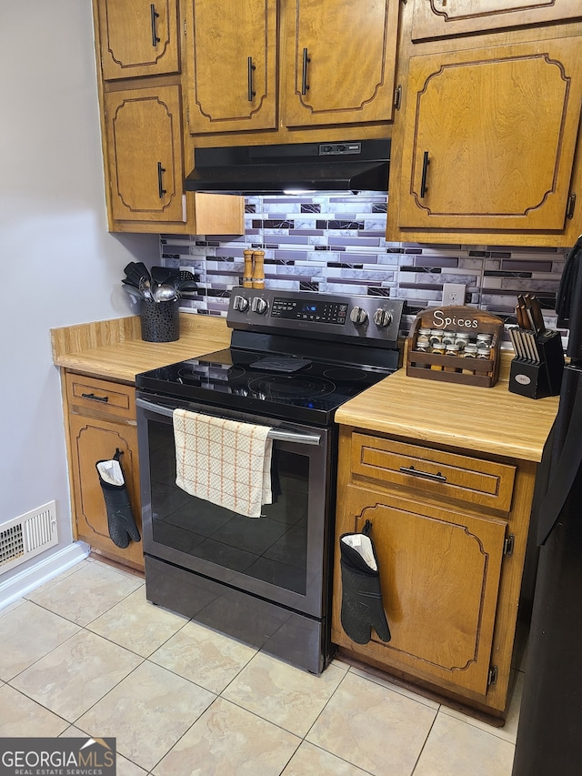 kitchen with exhaust hood, light tile patterned floors, tasteful backsplash, and electric range