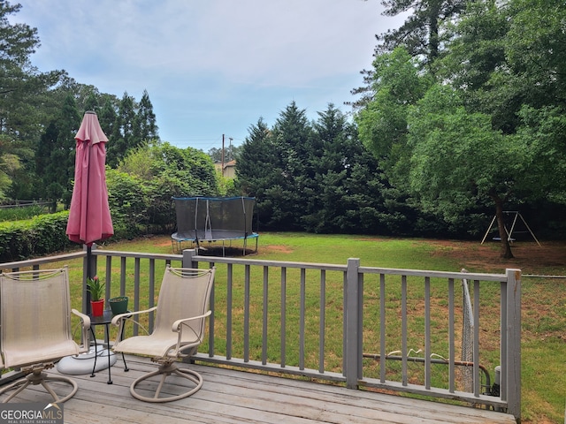 wooden terrace featuring a lawn and a trampoline