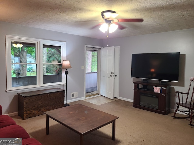 living room featuring a textured ceiling, light colored carpet, and ceiling fan