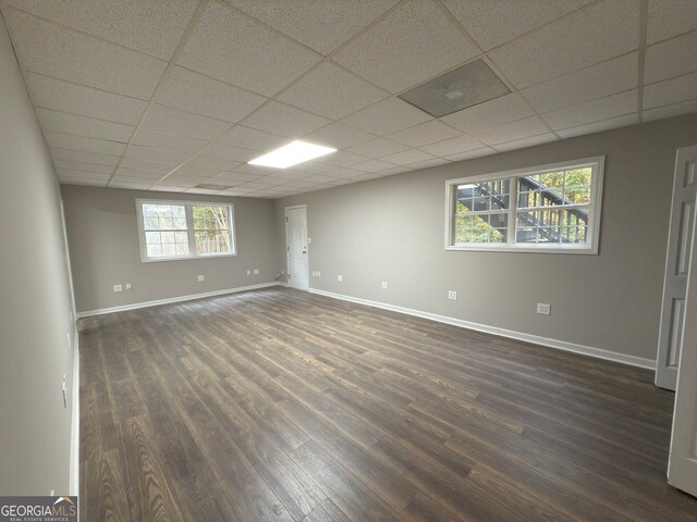 unfurnished room with a paneled ceiling, dark hardwood / wood-style flooring, and plenty of natural light