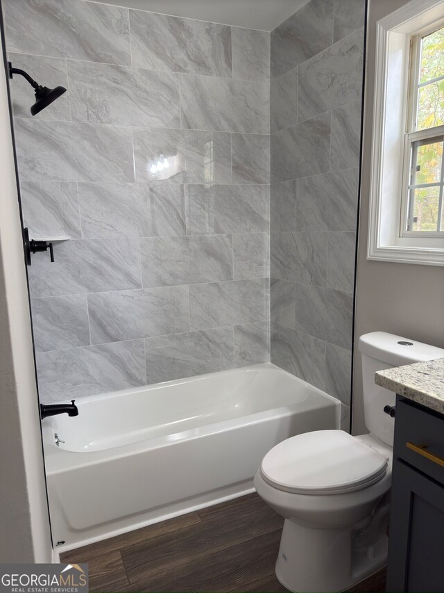 full bathroom with vanity, wood-type flooring, tiled shower / bath combo, and toilet