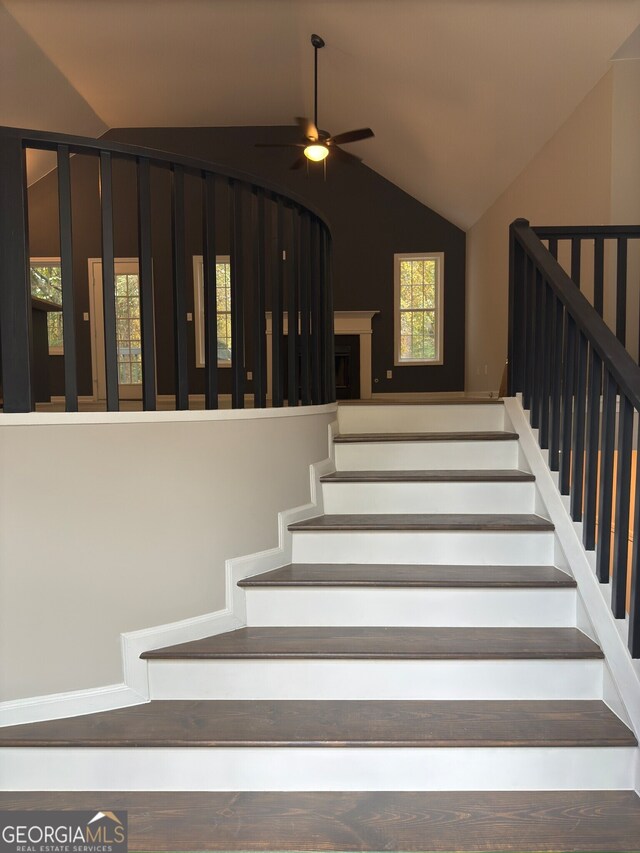 stairs with ceiling fan and lofted ceiling