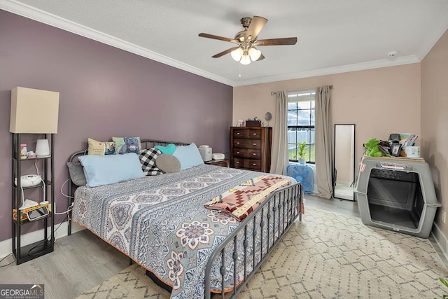 bedroom with a ceiling fan, wood finished floors, baseboards, and ornamental molding