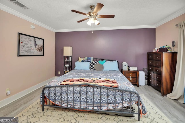 bedroom with visible vents, wood finished floors, a textured ceiling, and ornamental molding