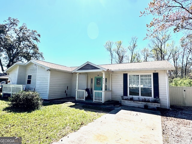 ranch-style home featuring covered porch, a front lawn, and fence