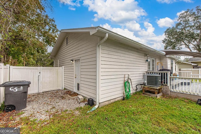 view of home's exterior featuring a gate, a yard, central AC, and fence