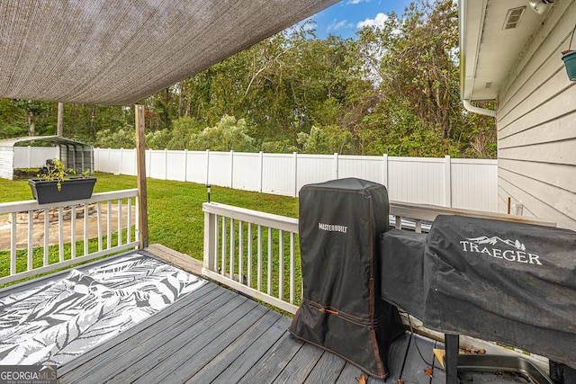 wooden terrace featuring a fenced backyard, a grill, an outdoor structure, and a yard