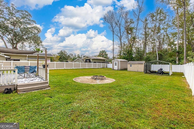 view of yard featuring a deck, a fenced backyard, a shed, a fire pit, and an outdoor structure